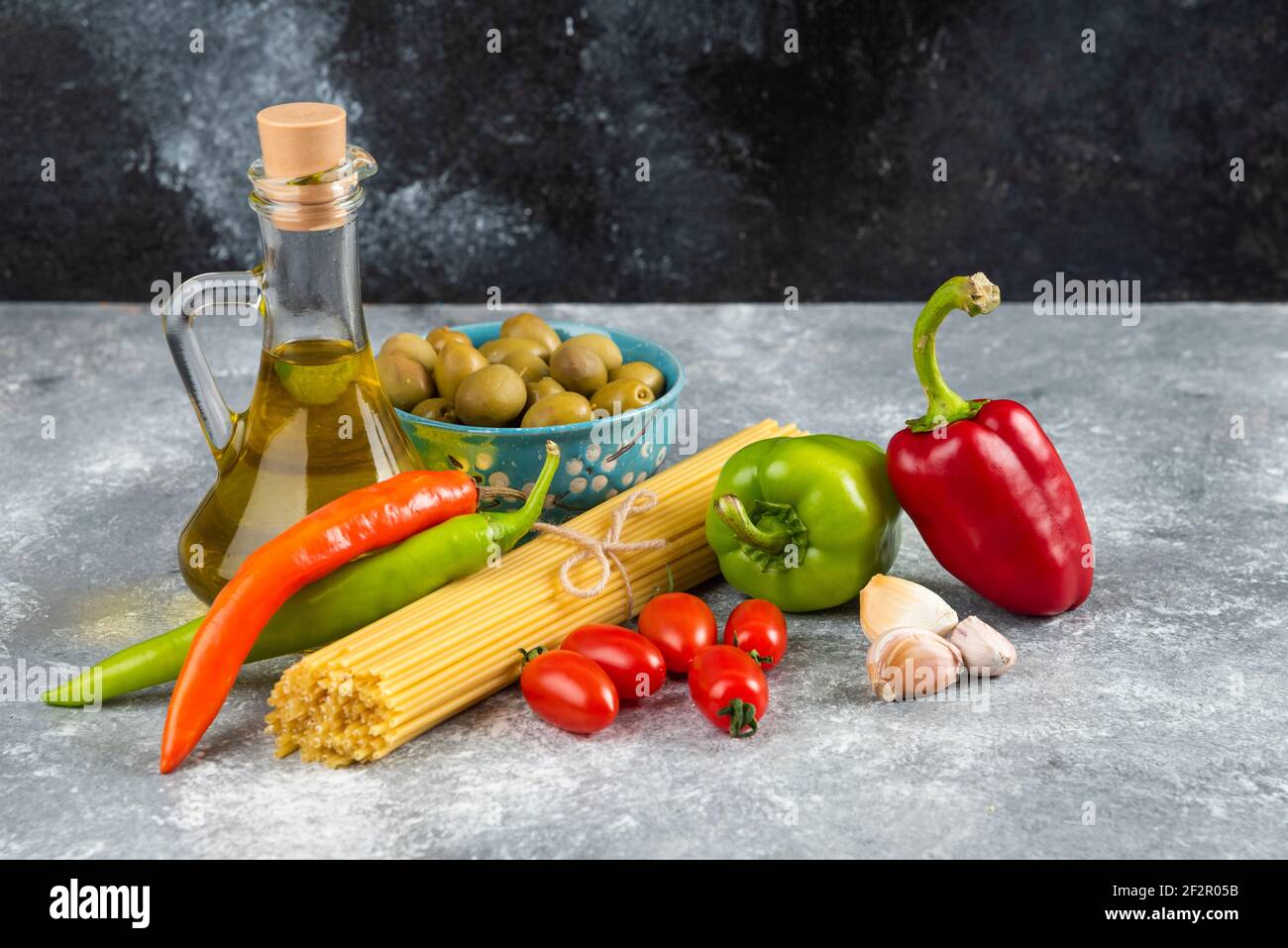 Spaghetti, Öl und verschiedene Gemüse auf Steintisch Stockfoto