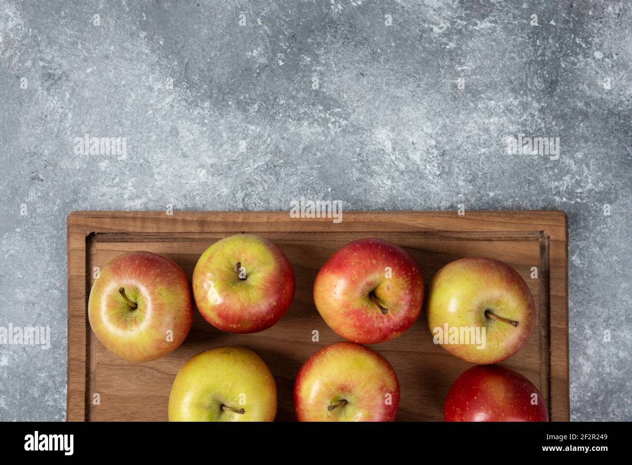 Holzbrett mit frischen leckeren Äpfeln auf Marmoroberfläche Stockfoto