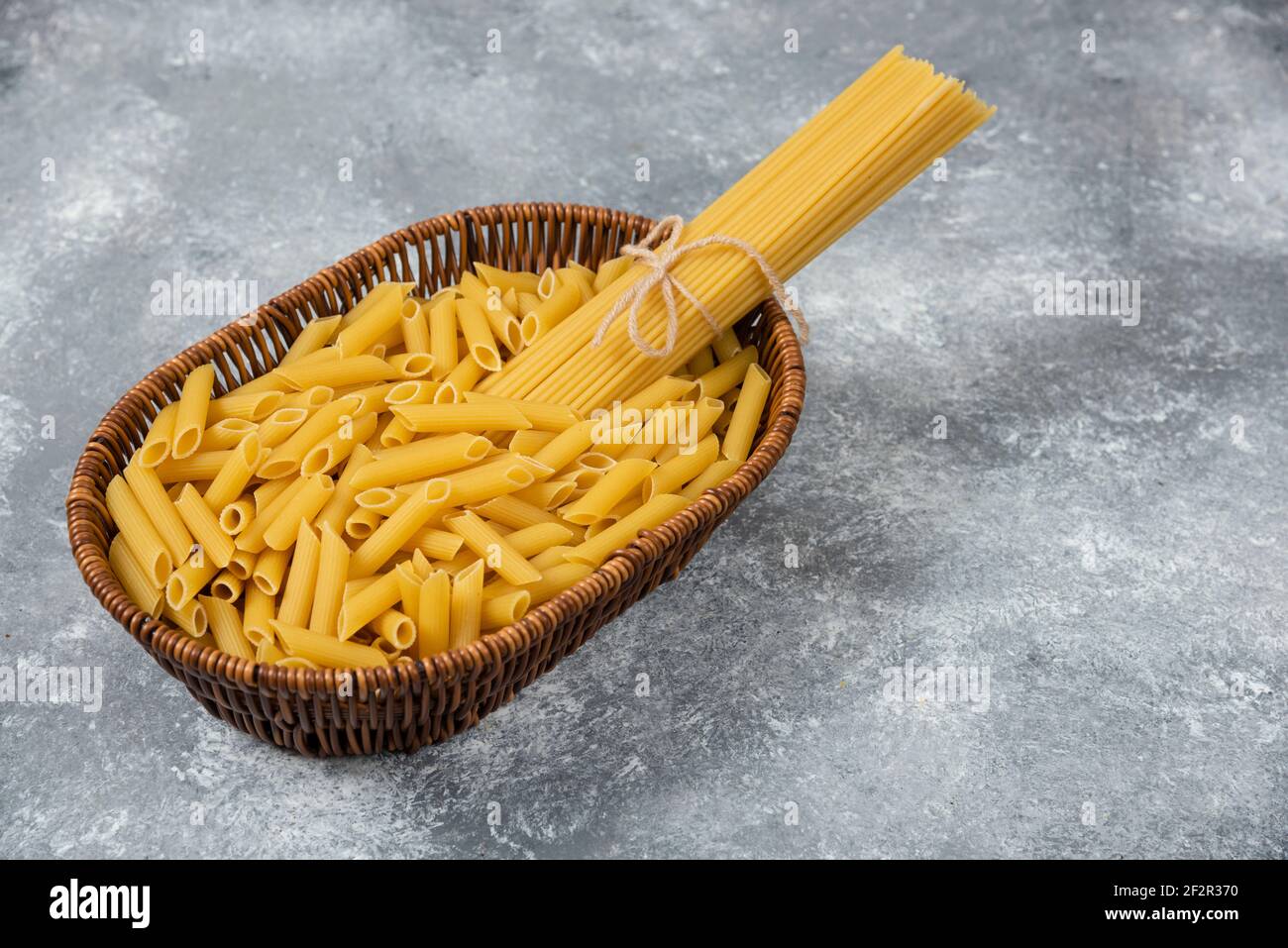 Korbkorb mit rohen Spaghetti und Penne Pasta auf Marmor Oberfläche Stockfoto