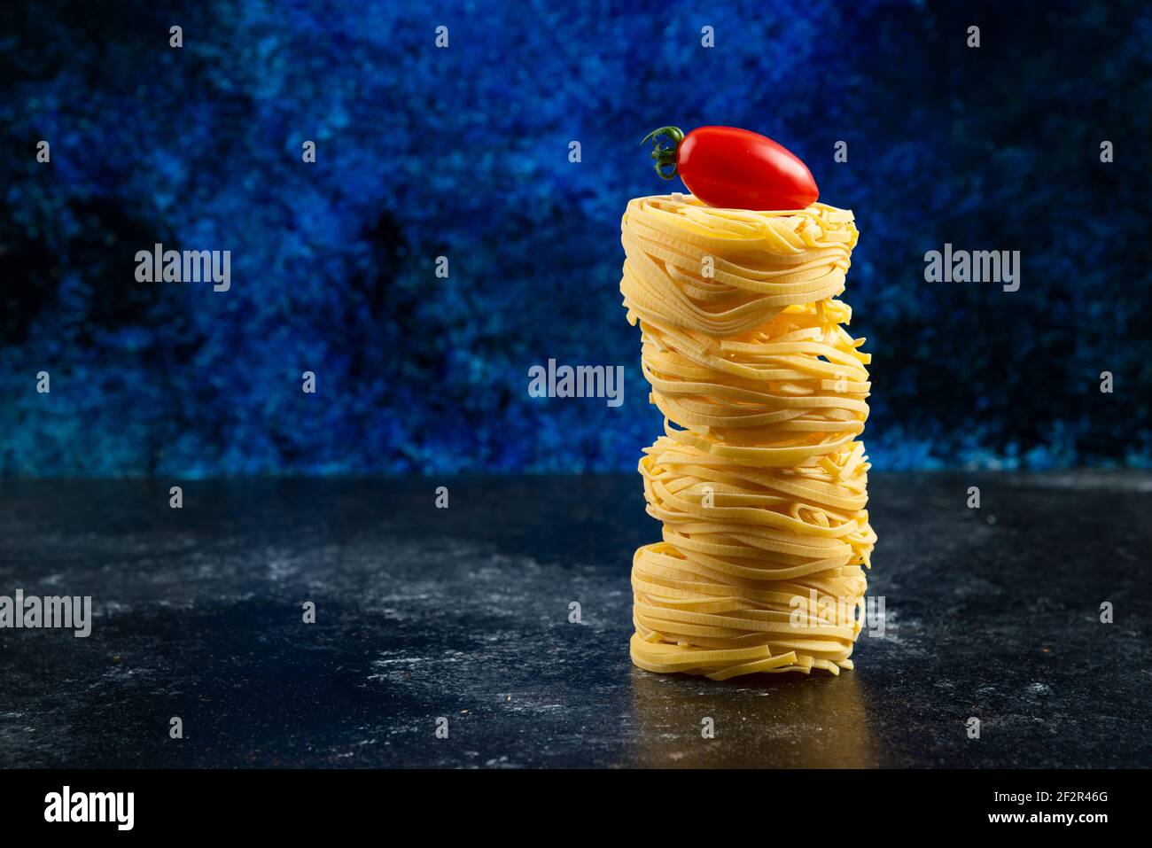 Ungekochte Nudelnester und Tomaten auf Marmortisch Stockfoto