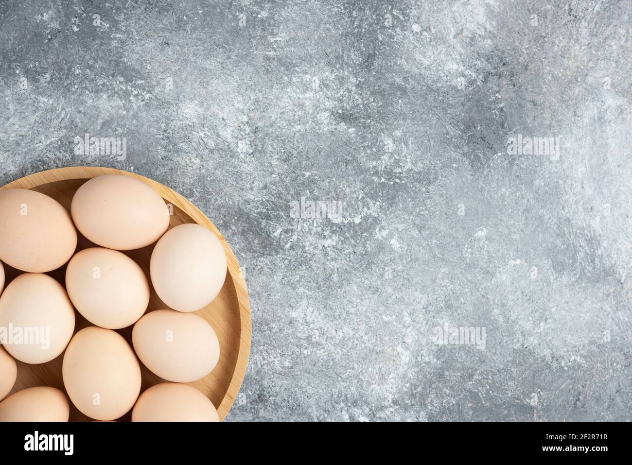 Holzplatte mit frischen Bio-rohen Eiern auf Marmoroberfläche Stockfoto