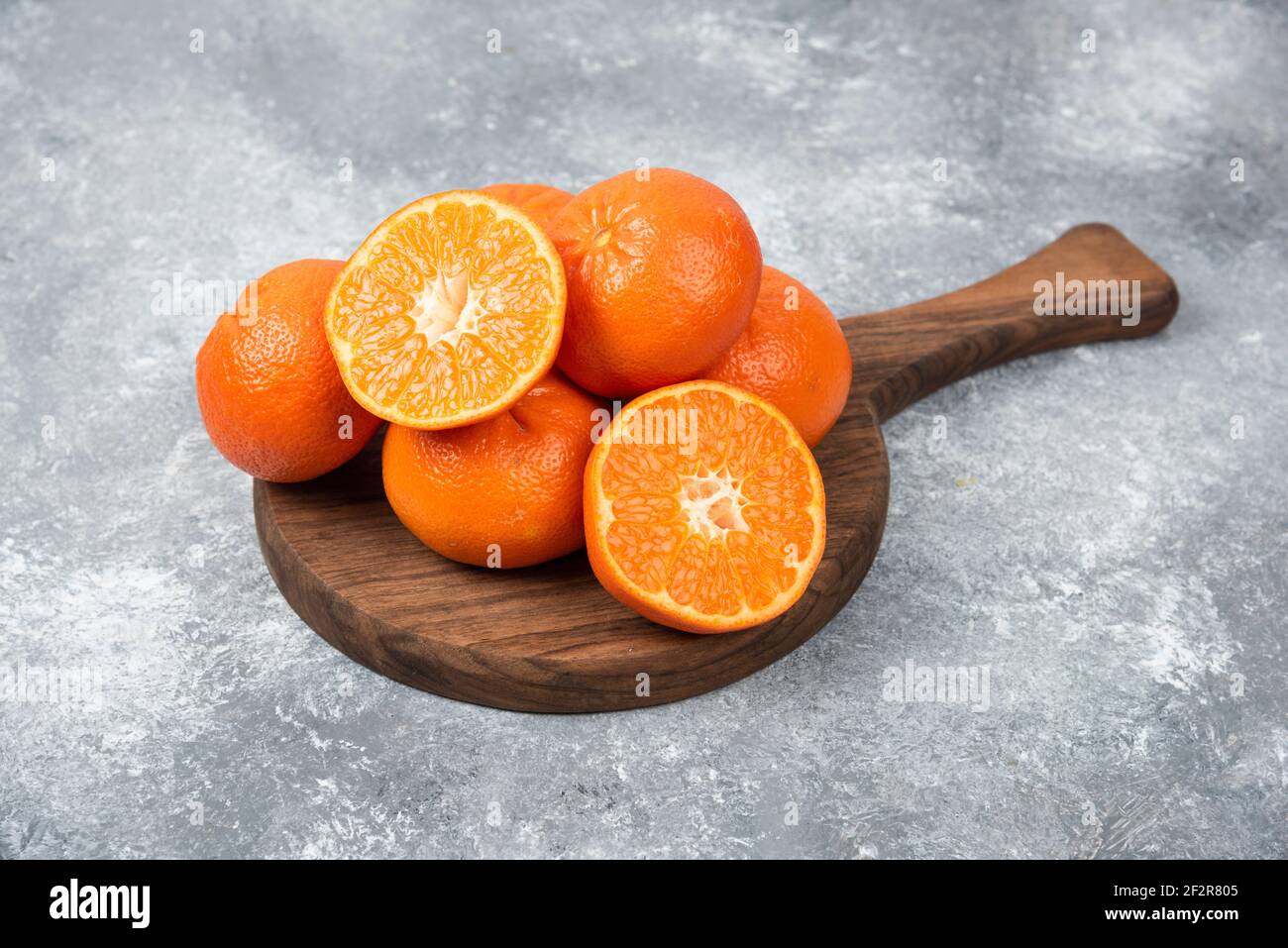 Ein Holzbrett voller saftiger Orangenfrüchte mit Scheiben Auf steinernem Hintergrund Stockfoto