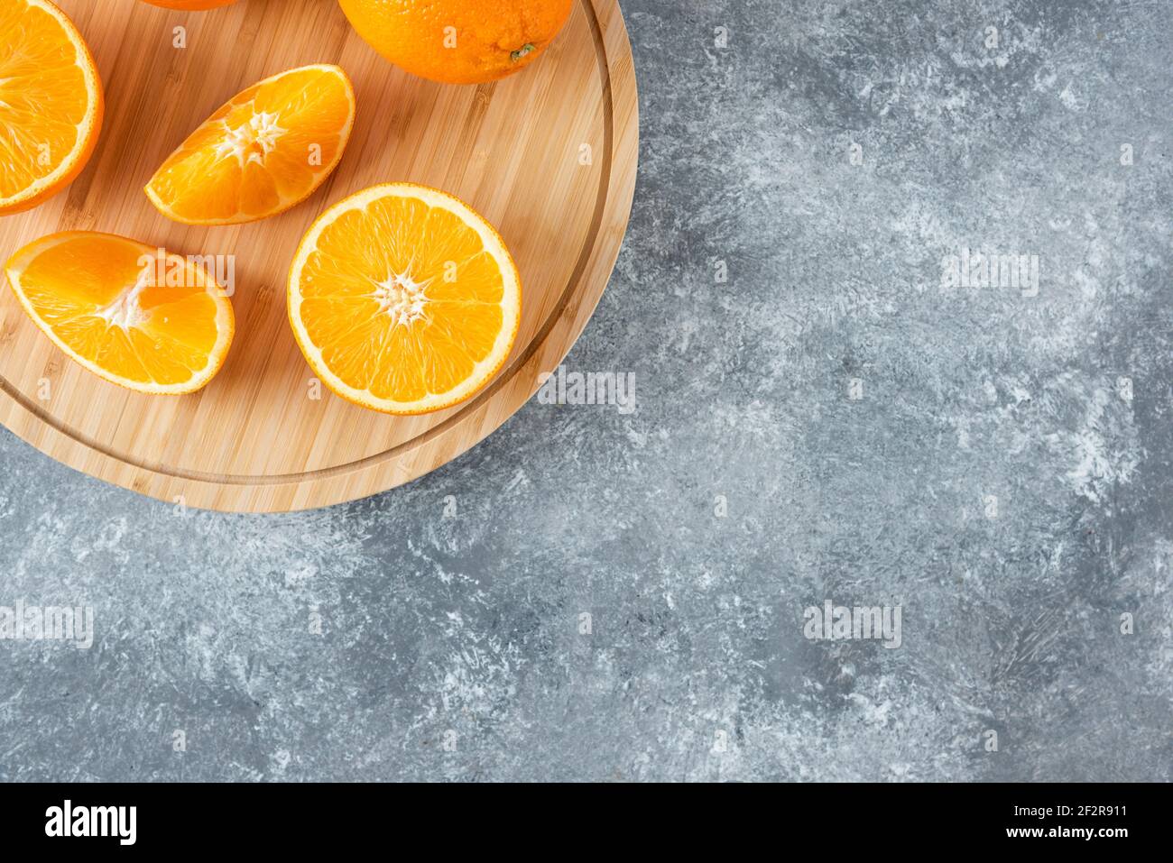 Ein Holzbrett voller saftiger Scheiben Orangenfrucht Auf steinernem Hintergrund Stockfoto