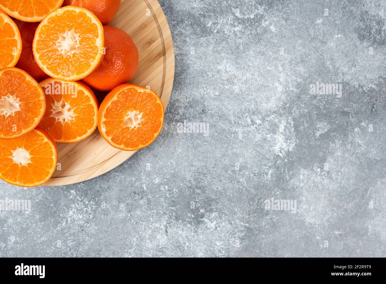 Saftige frische Orangenfrüchte in Scheiben geschnitten auf einem Holzteller Stockfoto