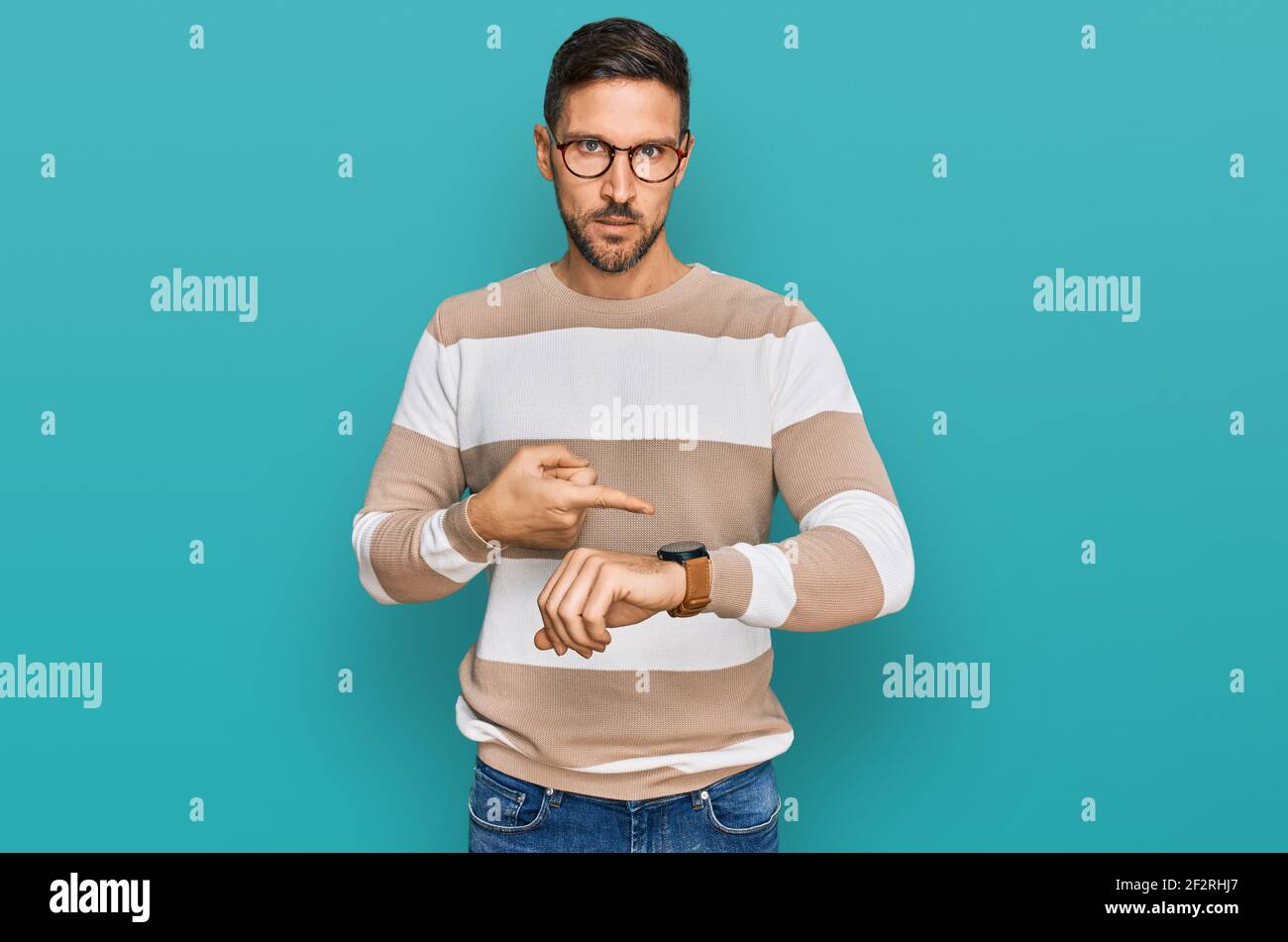 Gutaussehender Mann mit Bart tragen lässige Kleidung und Brille in Eile zeigt auf Zeit, Ungeduld, aufgeregt und wütend auf Deadline Verzögerung zu beobachten Stockfoto