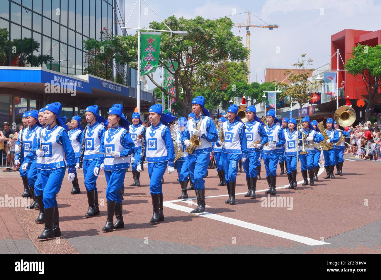 Mitglieder von Falun Dafa (Falun Gong), einer chinesischen Religion, marschieren in blau-weißen traditionellen Kleidern die Straße entlang und spielen Musikinstrumente Stockfoto