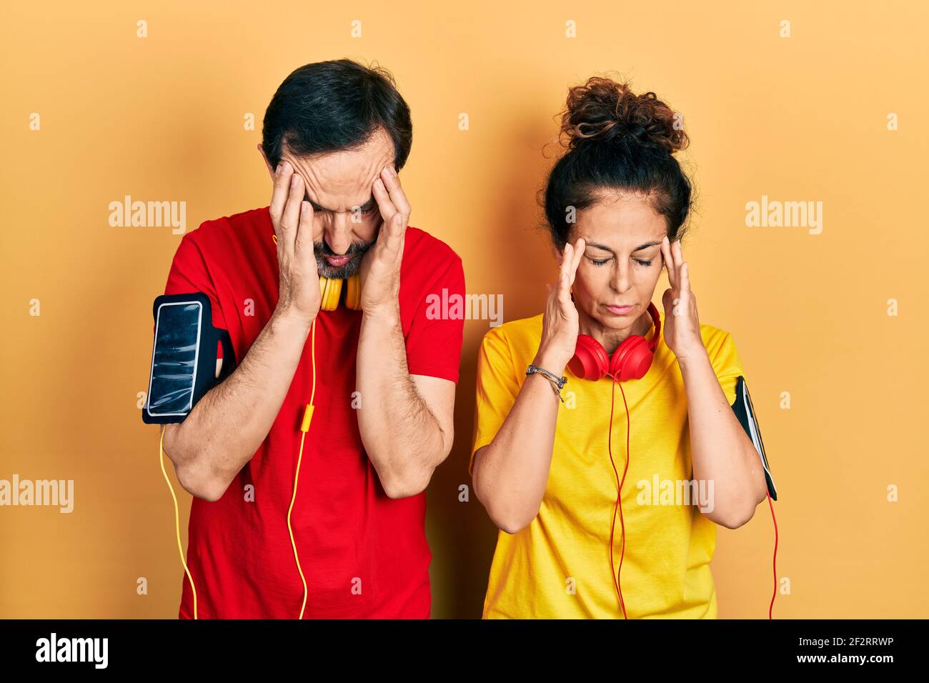 Mittelalterpaar hispanische Frau und Mann tragen Sportkleidung und Armband mit Hand am Kopf für Schmerzen im Kopf, weil Stress. Leiden Migräne. Stockfoto