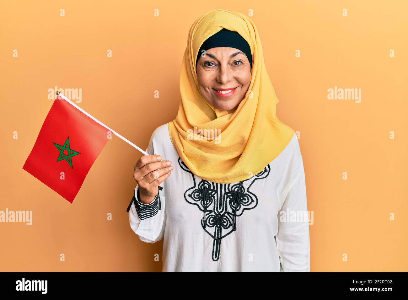 Mittelalter hispanische Frau trägt Hijab hält marokko Flagge suchen Positiv und glücklich stehen und lächeln mit einem selbstbewussten Lächeln Zeigt Zähne Stockfoto