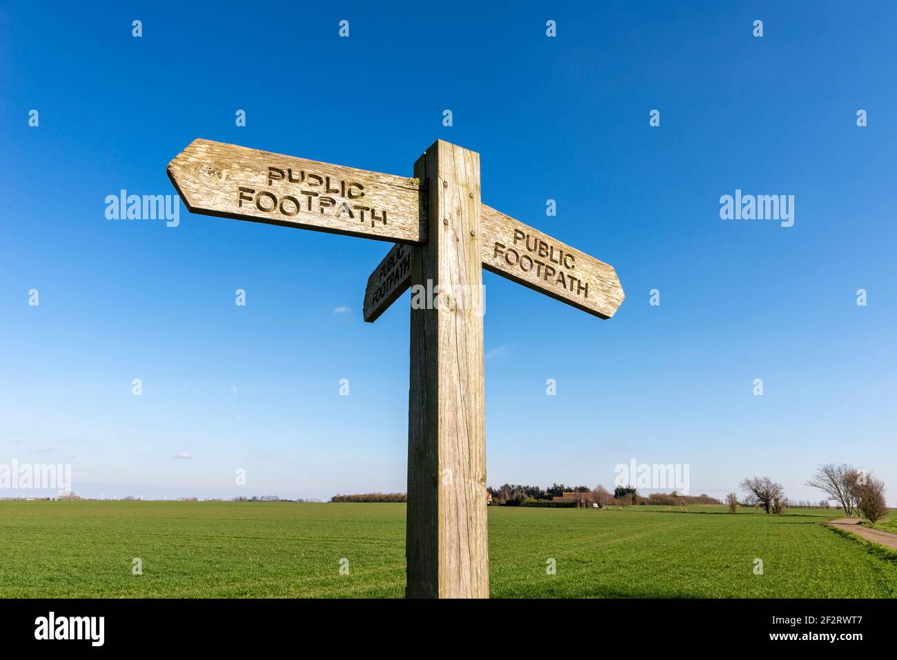 Alte hölzerne öffentliche Wanderweg Zeichen in einer ländlichen Gegend in der Nähe Stambridge in der Essex Landschaft. Isoliert gegen blauen Himmel. Text nicht gerade Stockfoto
