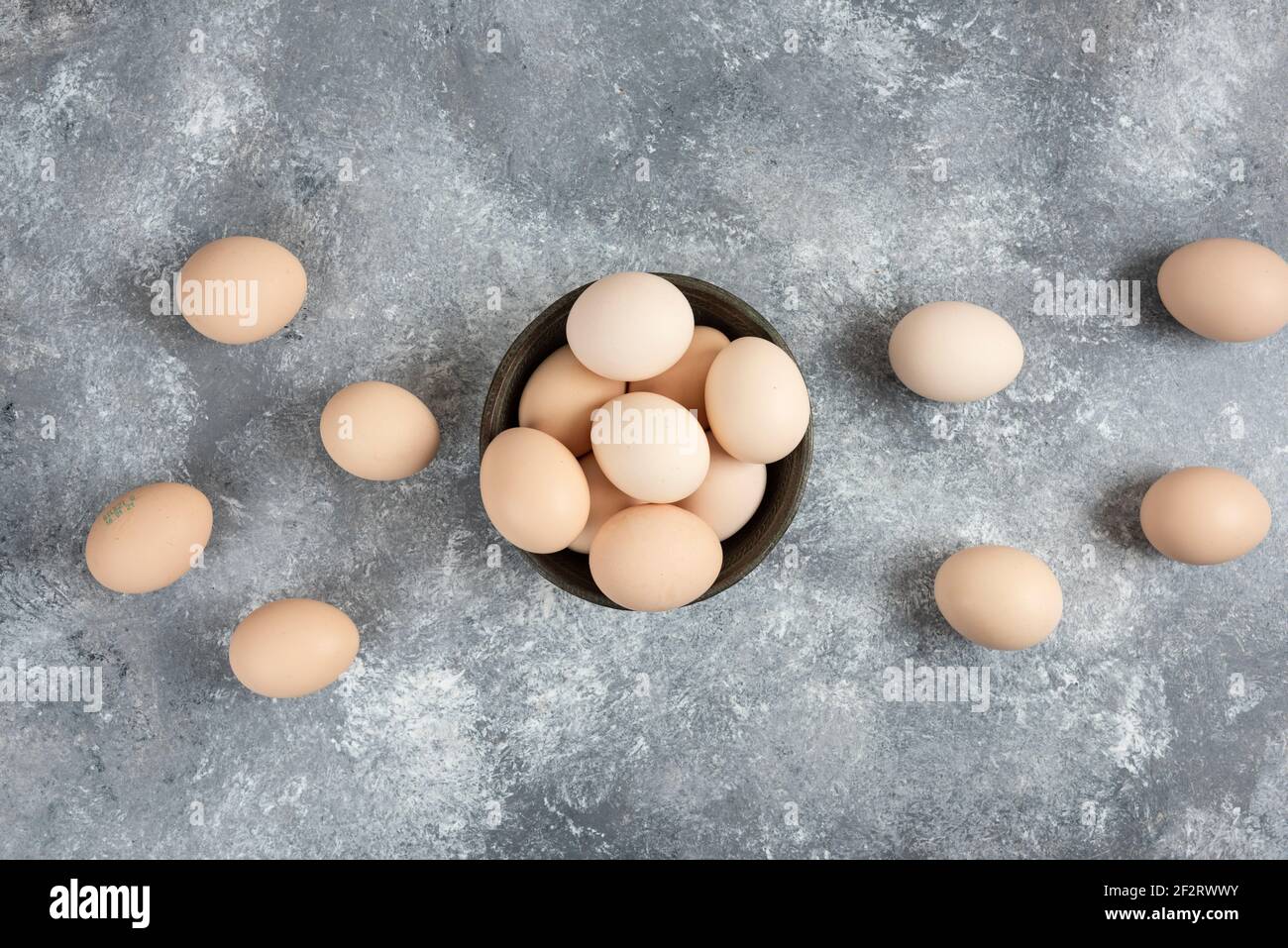 Holzschale aus Bio-rohen Eiern auf Marmoroberfläche platziert Stockfoto