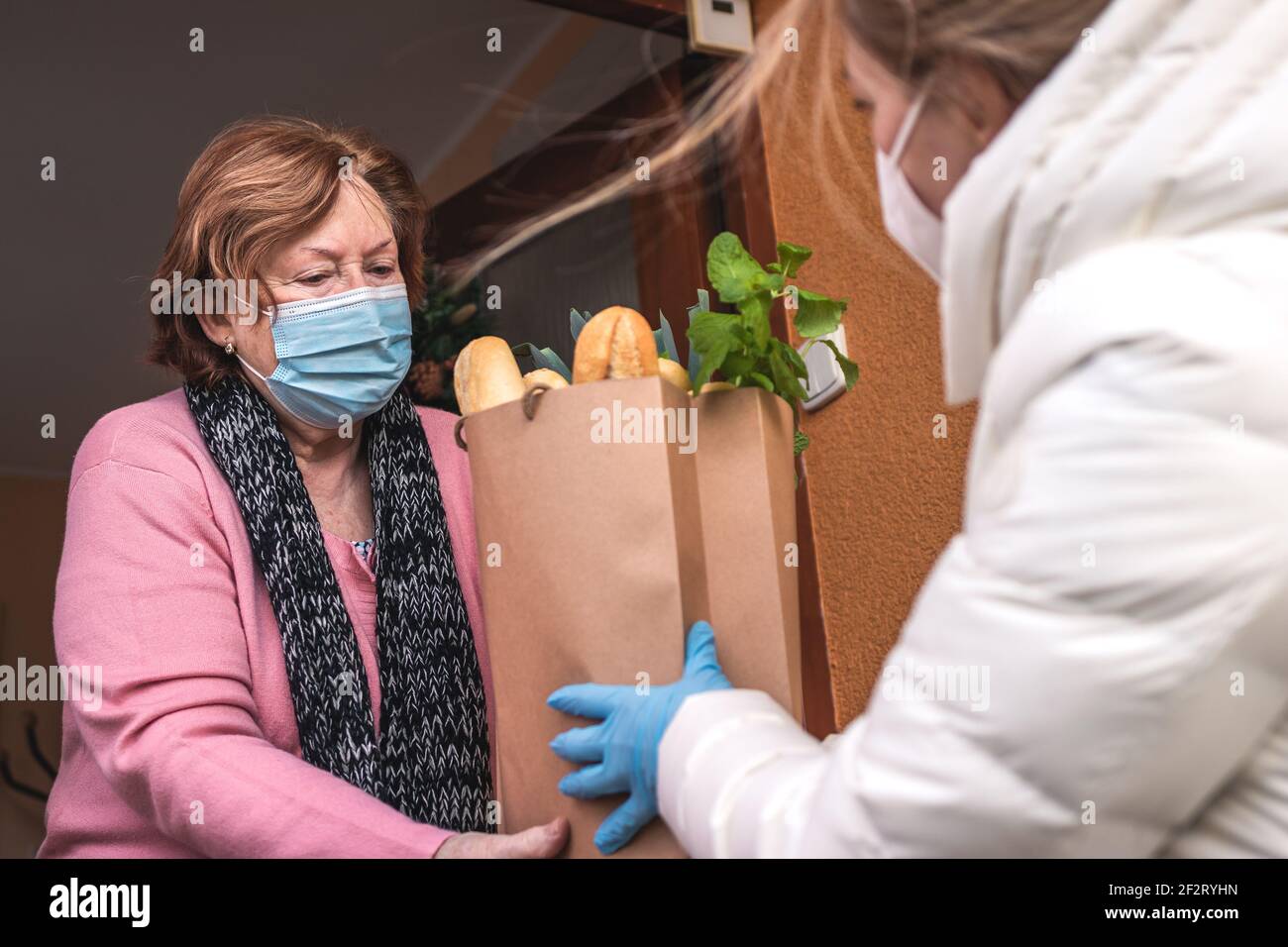 Unterstützen Sie Ihre Familie in schwierigen Zeiten. Erwachsene Tochter besucht ihre unter Quarantäne gestellte ältere Mutter und liefert Lebensmittel durch covid-19 Pandemie Sperrung Stockfoto
