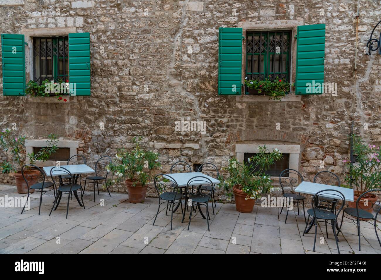Restauranttische in einer engen Straße in der Altstadt von Sibenik, Kroatien Stockfoto