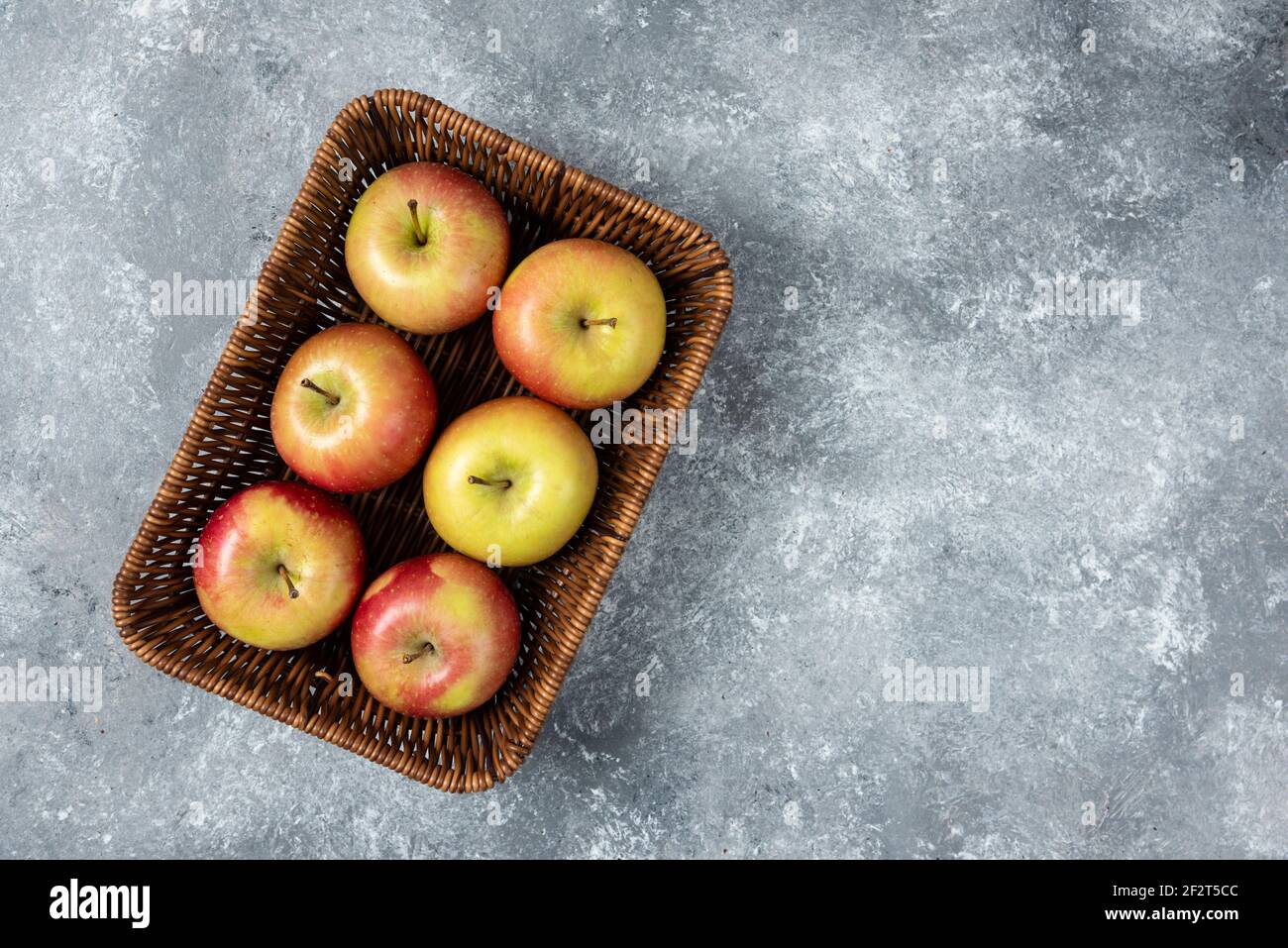 Korbkorb mit frischen saftigen Äpfeln auf Marmoroberfläche Stockfoto