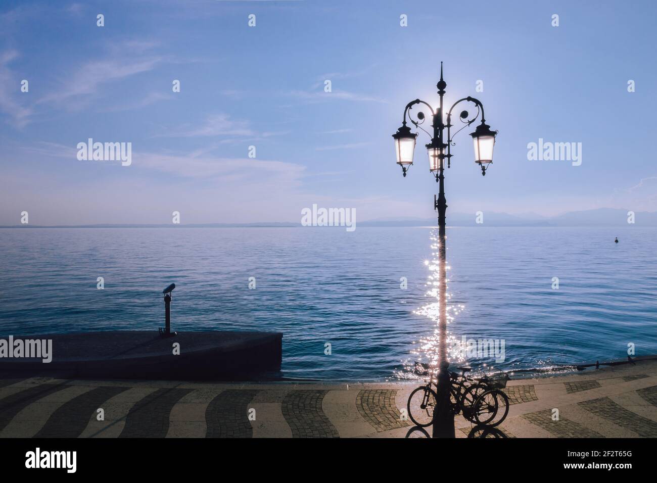 Minimalistischer Blick auf den Gardasee im Vordergrund ein Lampenstiel Und Fahrräder Stockfoto