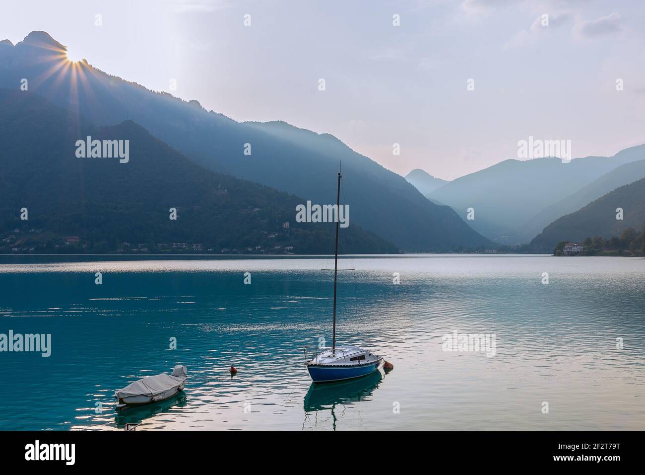 Eine minimalistische Landschaft des Idrosees mit einem Boot und Sonnig hinter den Felsen (Italien) Stockfoto