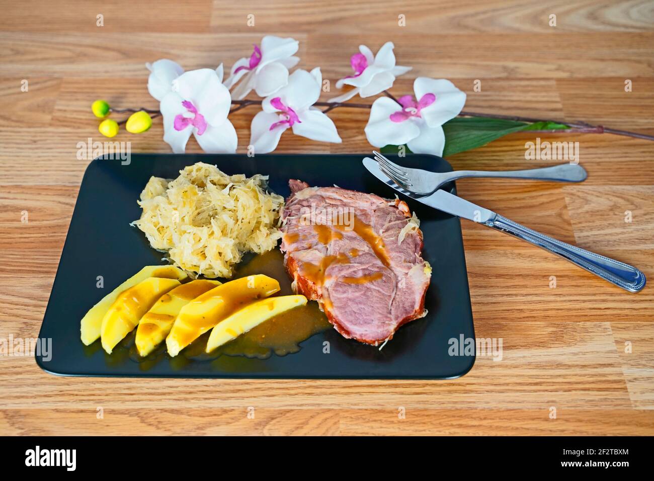 Gesalzenes Fleisch mit Sauerkraut und Kartoffelkeilen auf schwarz  angeordnet Platte Stockfotografie - Alamy