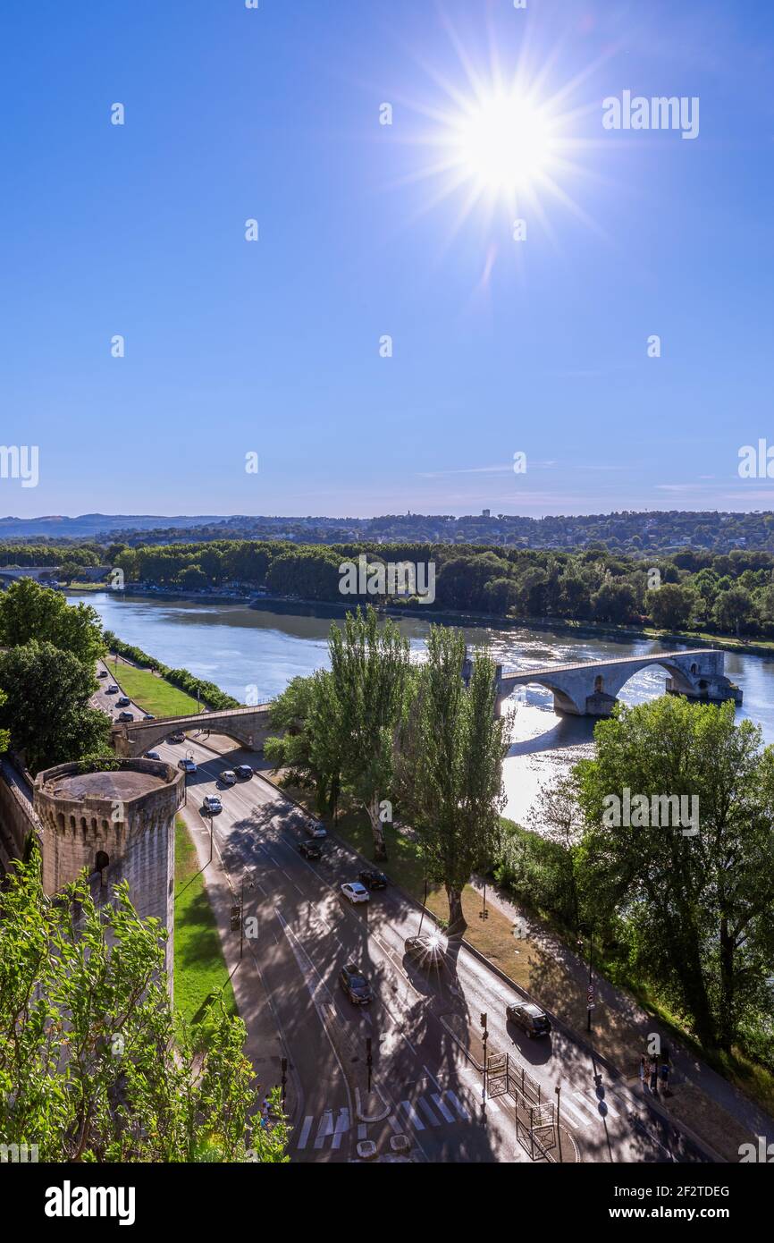 Ein heller Sonnenstrahl erhellt die Rhône und die Pont Saint-Benezet in Avignon, Frankreich, mit von Bäumen gesäumten Ufern und Stadtmauern, die von oben gesehen werden. Stockfoto