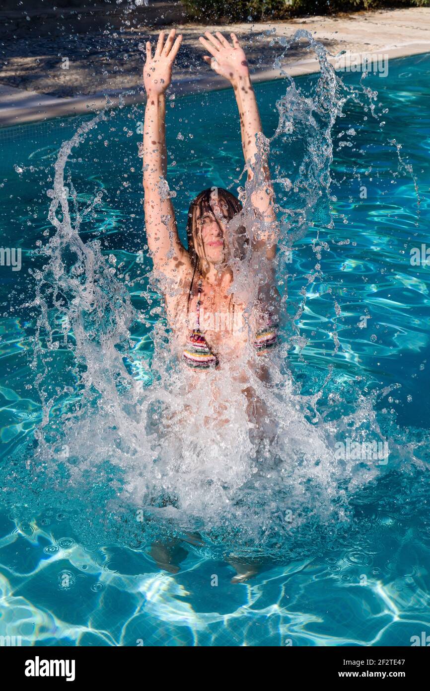 Hübsche junge Frau in blauem Bikini, die sich in und um ein Sommerschwimmbad amüiert Stockfoto