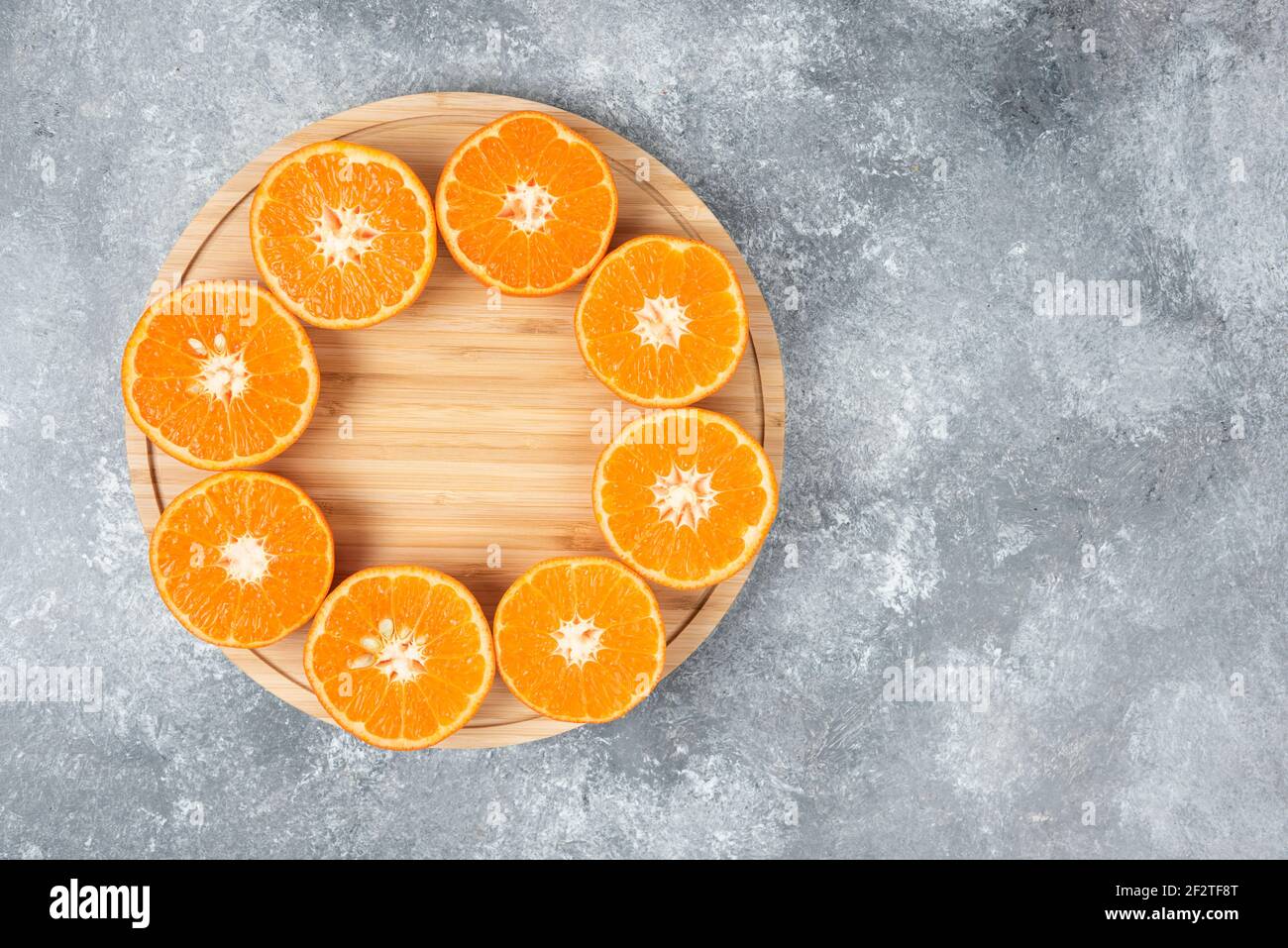 Saftige frische Orangenfrüchte in Scheiben geschnitten auf einem Holzteller Stockfoto