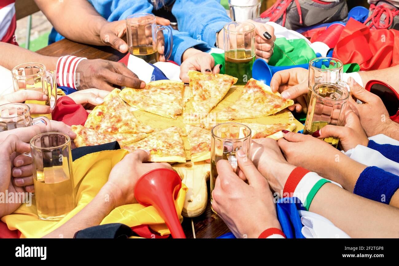 Draufsicht auf die multirassischen Hände von Fußballfreunden-Unterstützern Teilen Pizza margherita im Restaurant Stockfoto