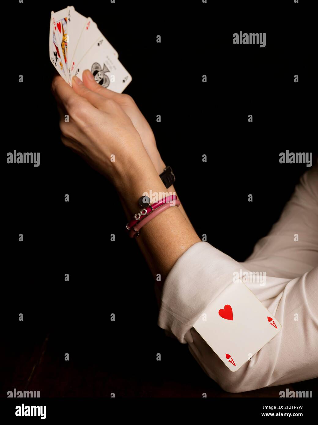 Eine Frau spielt Poker mit einem Ass von Herzen versteckt In die Manschette ihres weißen Hemdes Stockfoto