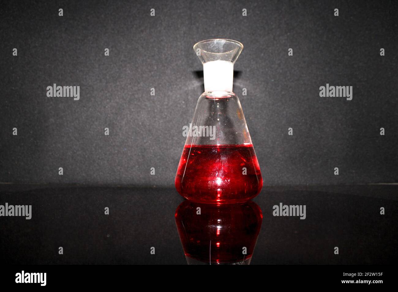 Eine Nahaufnahme einer Flasche mit roter Flüssigkeit auf einem Schwarzer Hintergrund Stockfoto