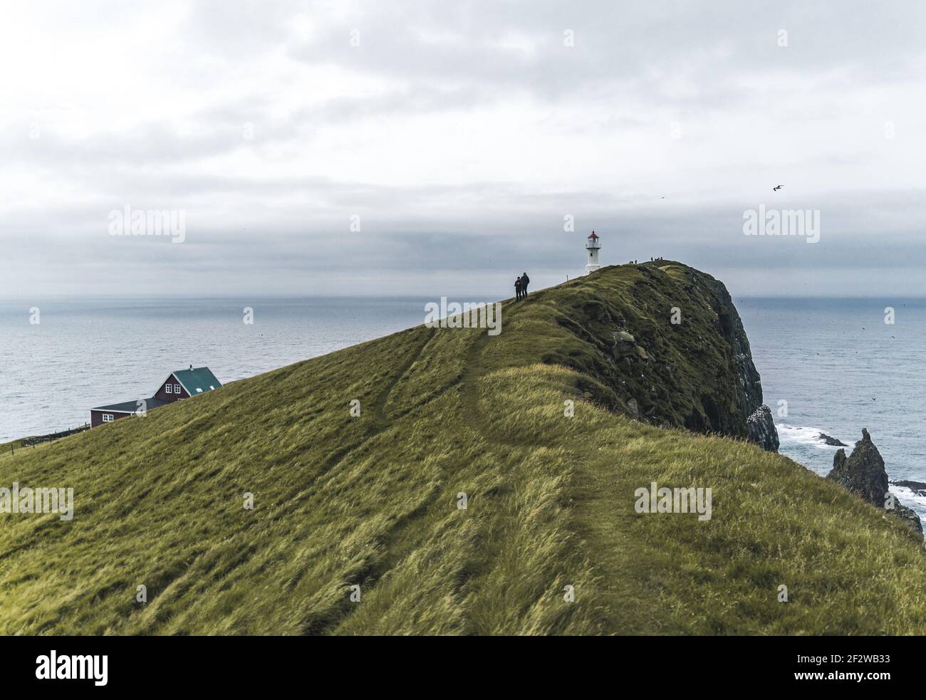 Blick zum Leuchtturm auf der Insel Mykines Holmur, Färöer Insel ein bewölktes Tag mit Blick auf den Atlantik. Stockfoto