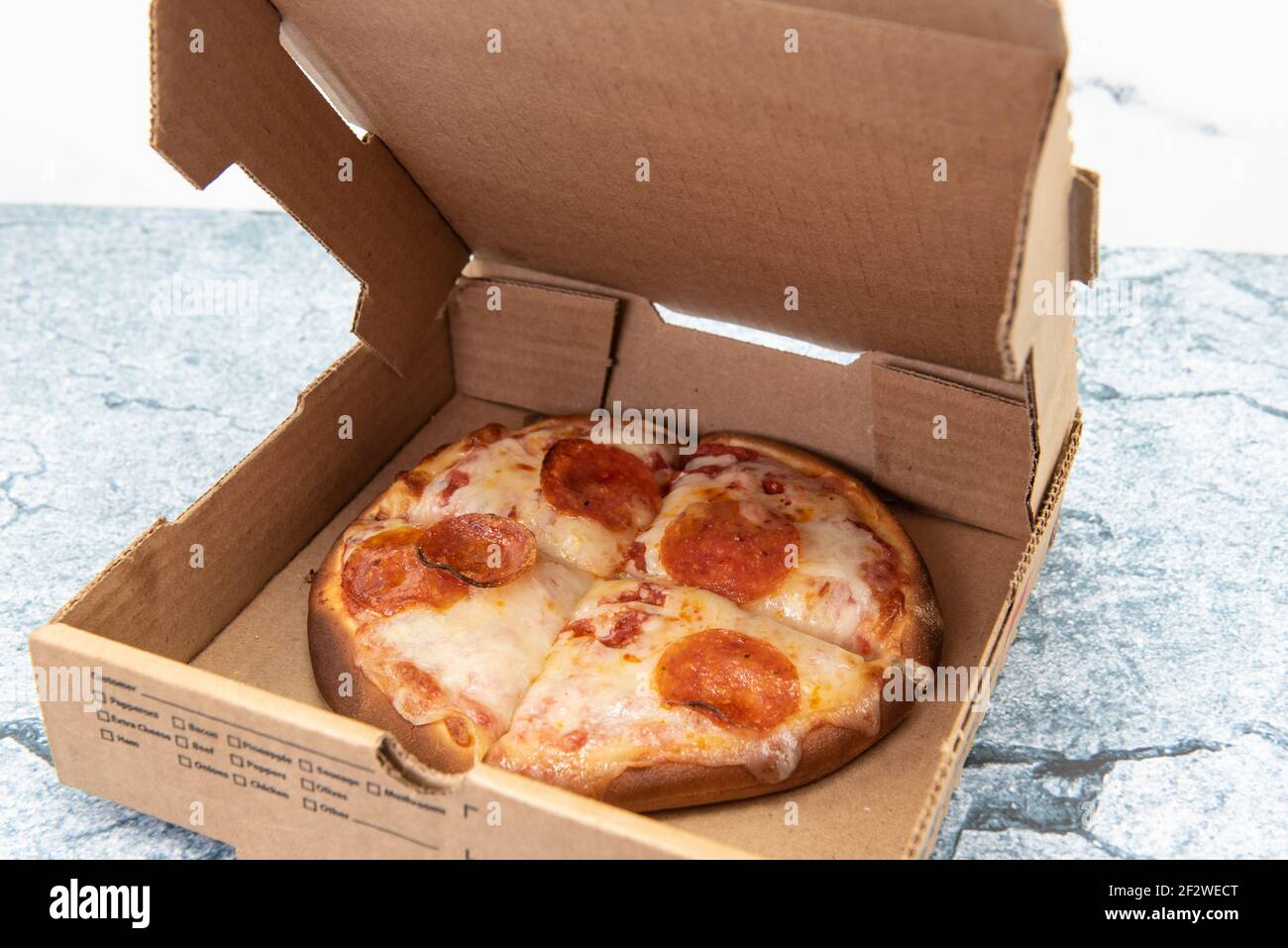 Kleine persönliche Pfanne Pizza in vier Scheiben geschnitten und in Karton geliefert. Stockfoto