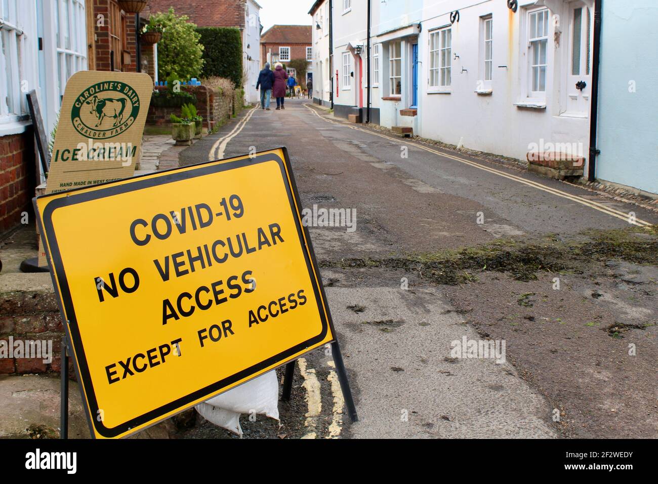 Covid-19 Warnschild weist auf keinen Fahrzeugzugang außer für den Zugang. Widersprüchliche Führung in einer kleinen, engen Straße in Bosham. Eisschild Stockfoto