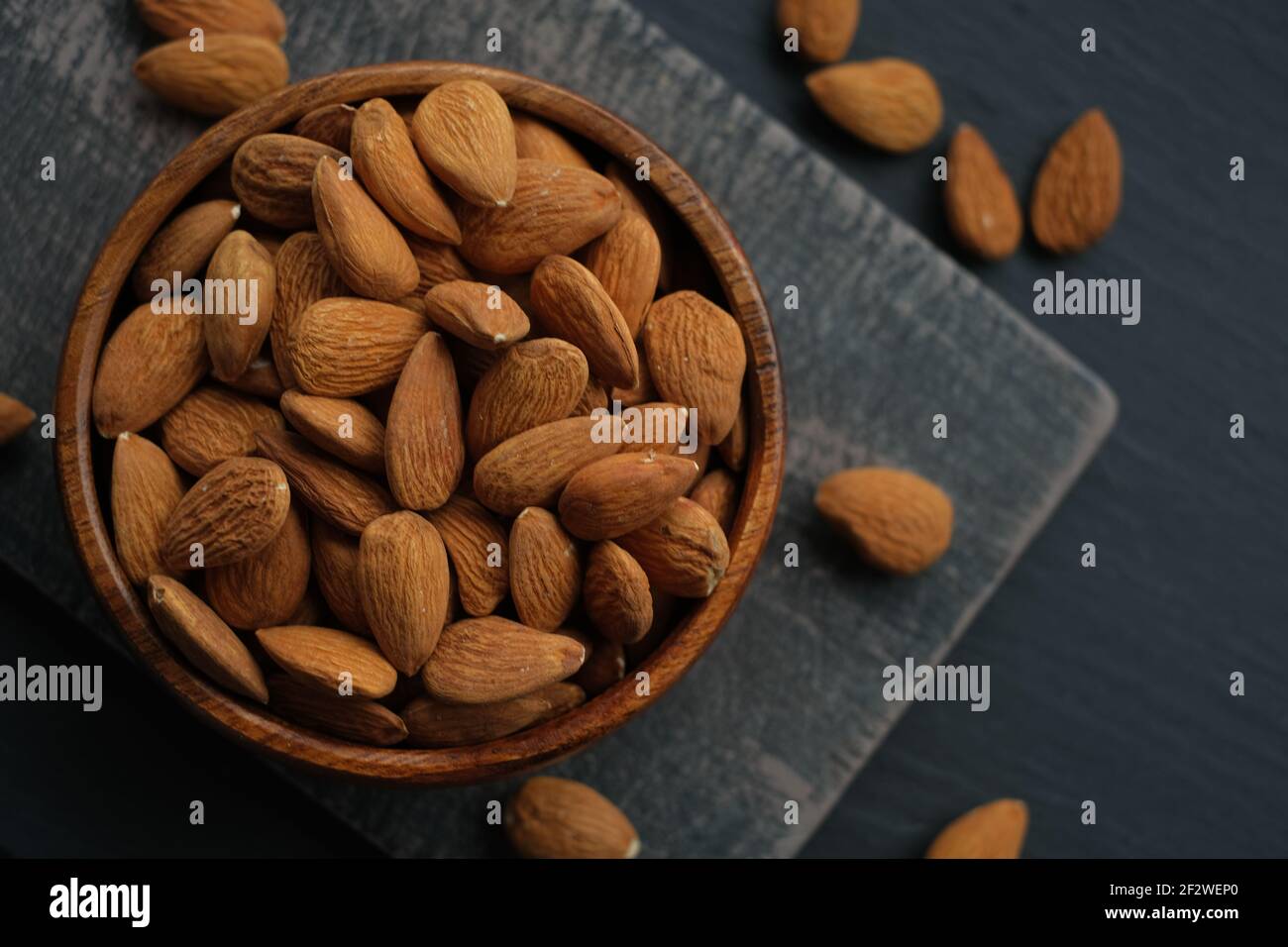 Mandeln Nüsse Nahaufnahme in einer Tasse auf einem schwarzen schäbig Chic Board auf einem schwarzen schiffer verschwommen Hintergrund.Nüsse .gesunde Fette.Heap Mandeln geschälte Nuss Nahaufnahme Stockfoto