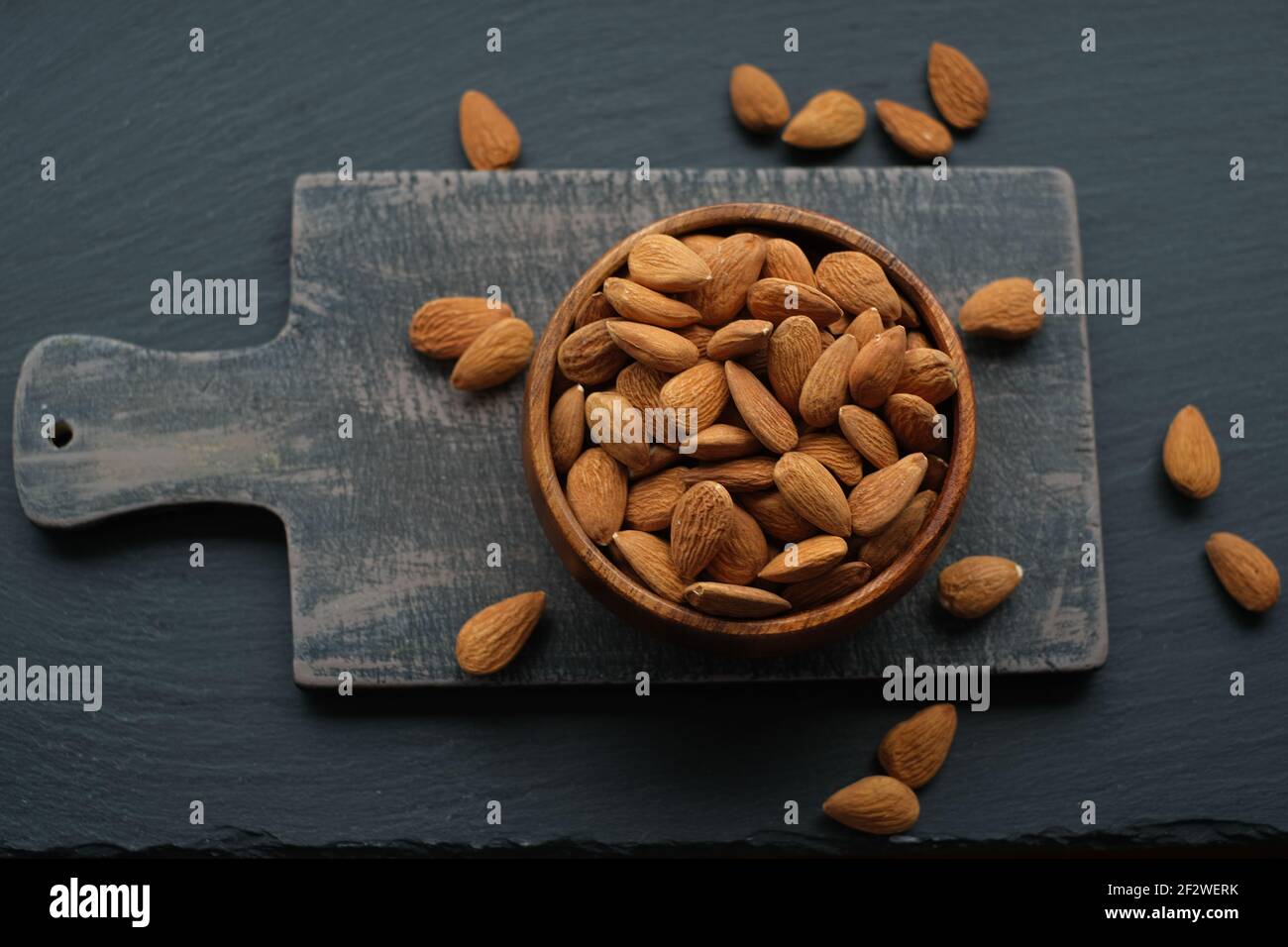 Mandeln Nüsse Nahaufnahme in einer Tasse auf einem schwarzen Shabby Chic Board auf einem schwarzen schiffer Hintergrund.Nüsse und Samen. .gesunde Fette.Heap Mandeln geschälte Mutter Stockfoto