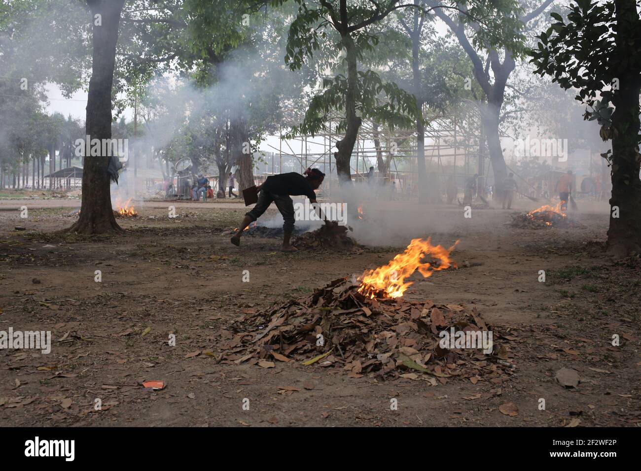 Dhaka, Bangladesch. März 2021, 13th. Getrocknete Blätter werden verbrannt, um den Park am Suhrawardi Uddan zu räumen.die Amar Ekushey Buchmesse 2021 beginnt in wenigen Tagen.in diesem Jahr beginnt die Buchmesse wegen des neuartigen Coronavirus spät.das Brennen von Blättern führt zu Luftverschmutzung, Gesundheitsproblemen und Brandgefahren. Kredit: MD. Rakibul Hasan/ZUMA Wire/Alamy Live Nachrichten Stockfoto