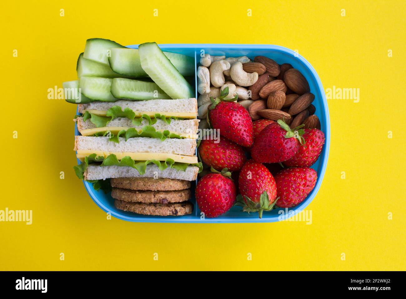 Mittagessen in der blauen Box in der Mitte des gelben Hintergrunds. Draufsicht. Stockfoto