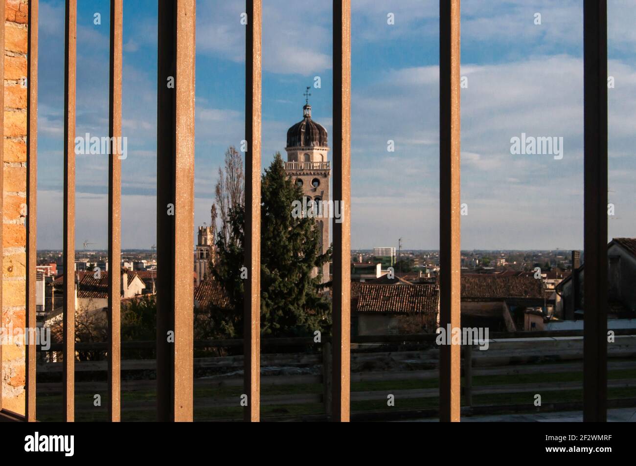 Blick durch einen Metallzaun auf eine Kirche. Wir trafen uns in Conegliano Italien an einem stimmungsvollen Spätsommerabend Stockfoto