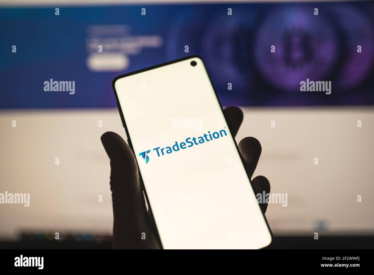 Mann hält ein Smartphone mit TradeStation Logo mit verschwommener Website als Hintergrund. Online-Brokerage, Trading-Service Stockfoto