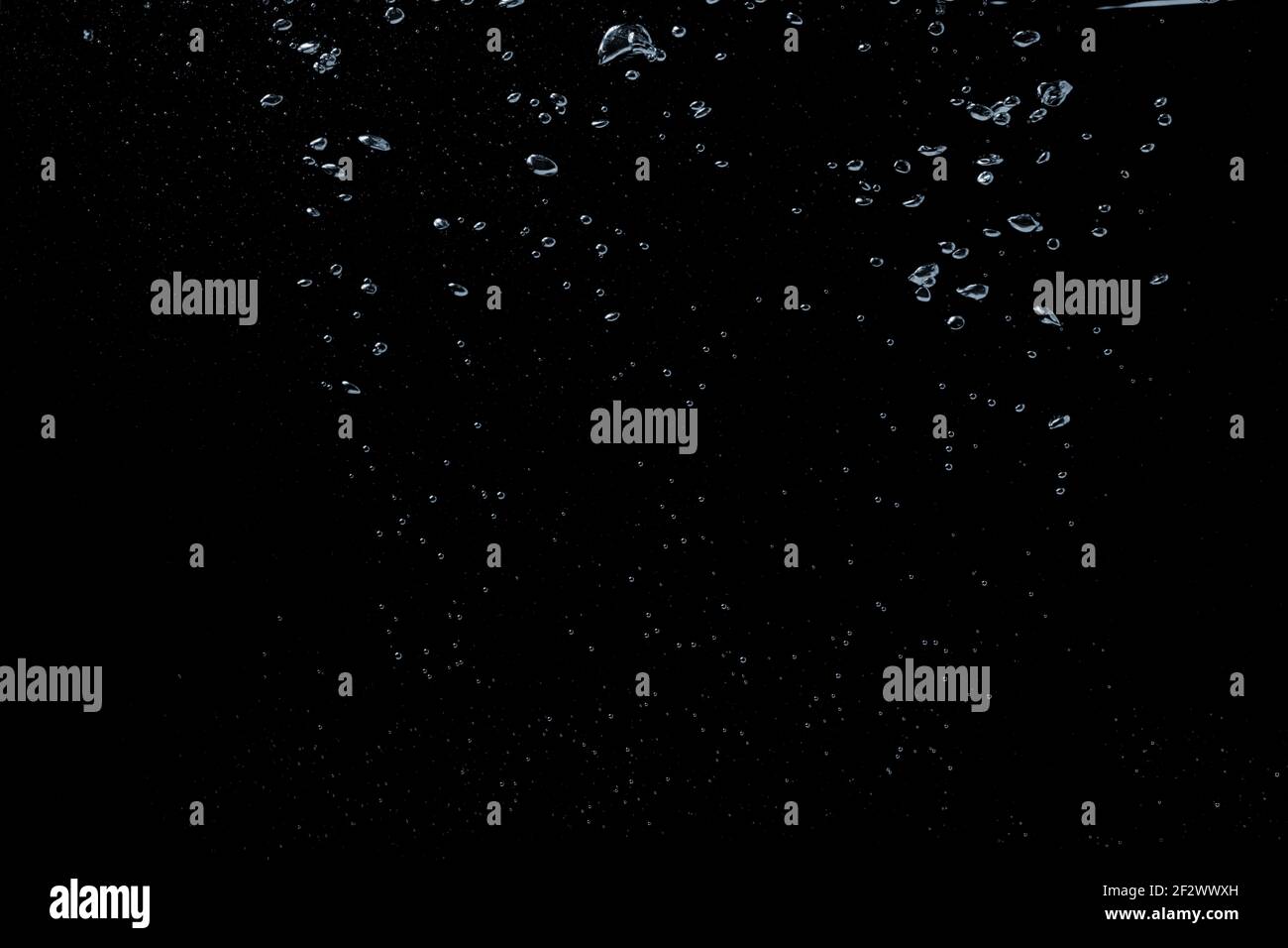 Eine Blase spritzt in durchsichtige klare Wasserflüssigkeit auf ein Schwarzer Naturhintergrund Stockfoto