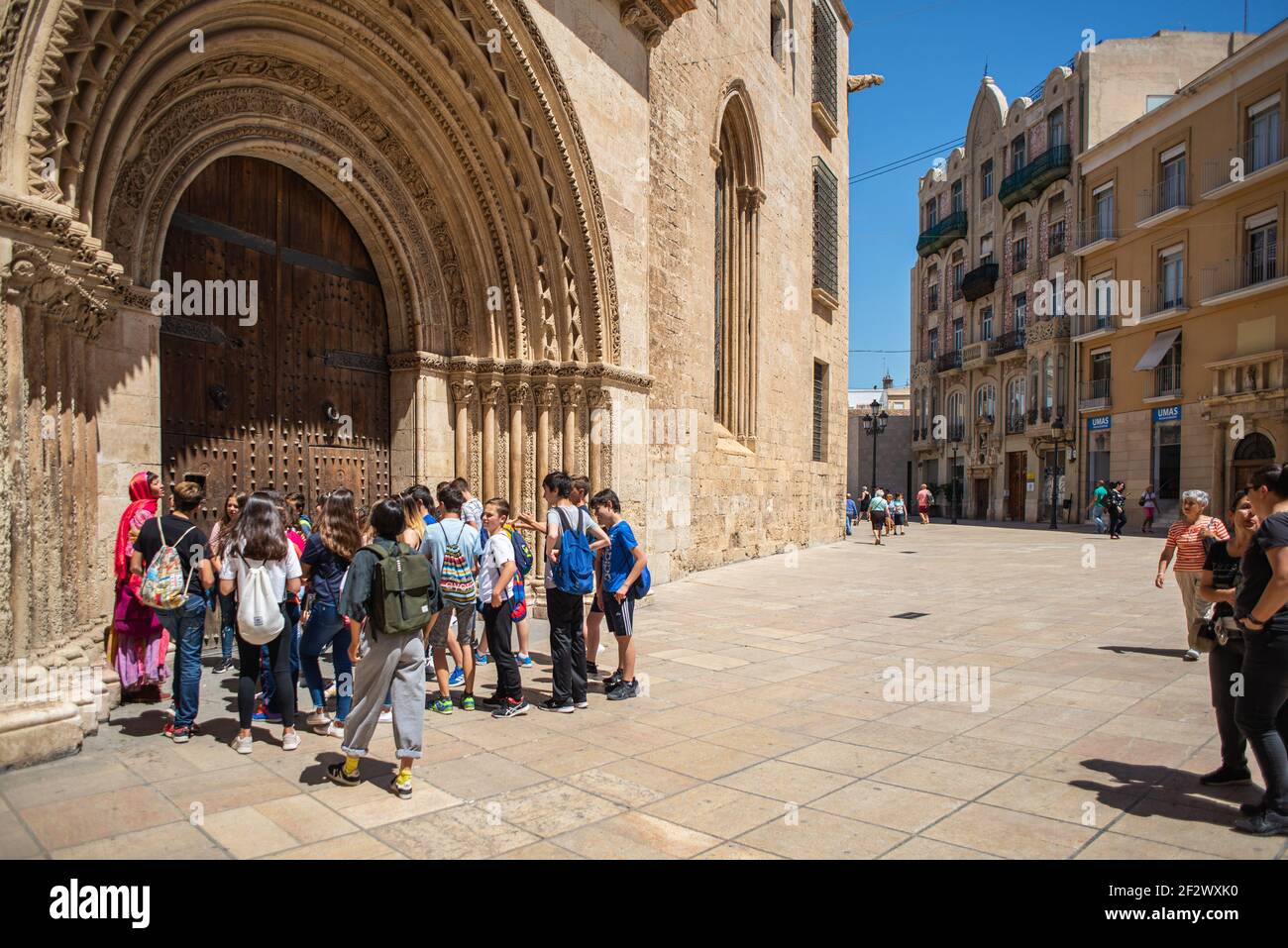 Eine Gruppe von Studenten vor einer mittelalterlichen Kirche in der Innenstadt von Valencia, Spanien. Valencia ist ein beliebtes Ziel für Bildungsreisen Stockfoto