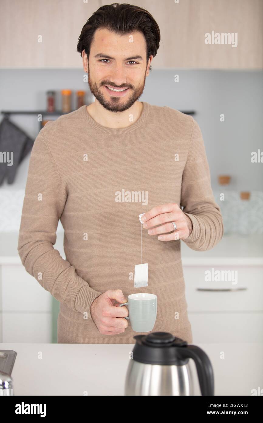 Mann hält Teebeutel über einer Tasse Stockfoto