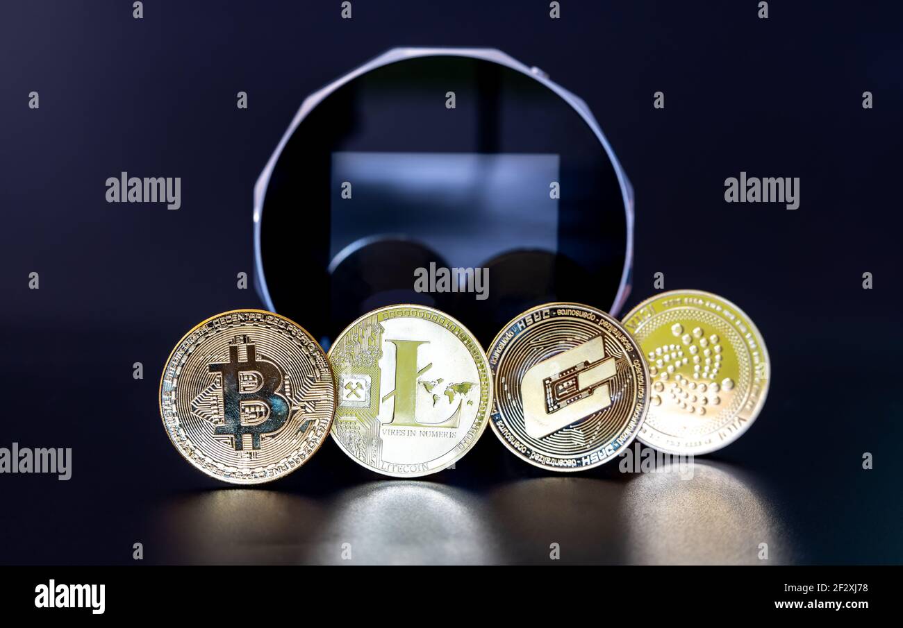 Die Krypto-Münzen Bitcoin, Litecoin, Dash und Iota vor einer digitalen Brieftasche. Stockfoto