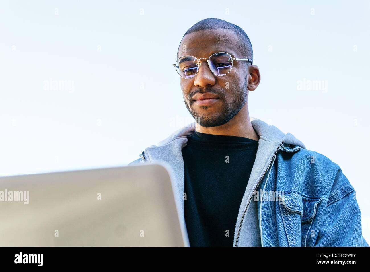 Von unten ethnisch afroamerikanischen erwachsenen männlichen entfernten Mitarbeiter mit Laptop in der Stadt Stockfoto