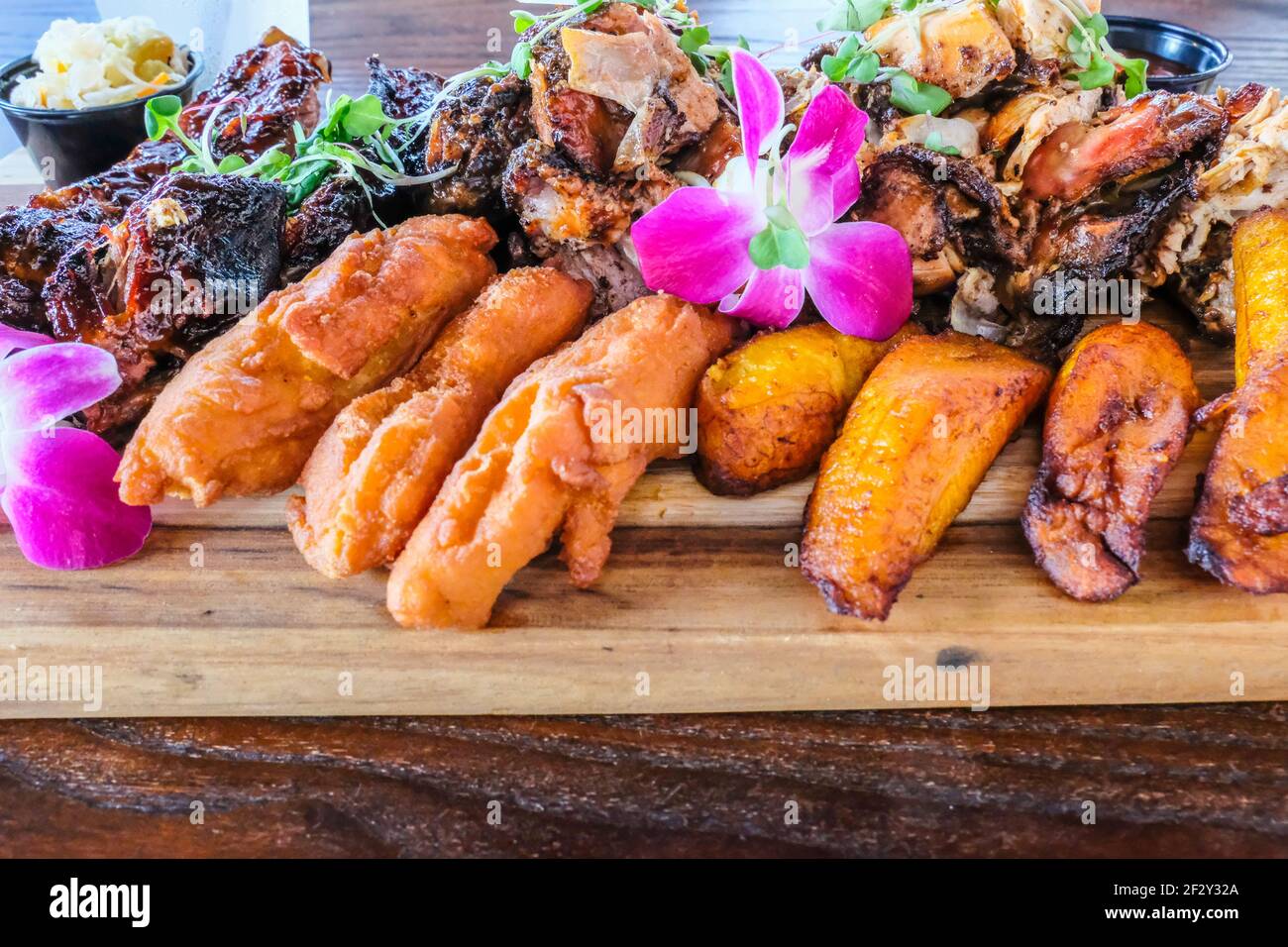 Teller mit tropischen Lebensmitteln Jerk Chicken BBQ Ribs Gebratene Kochbananen Auf einer Platte Stockfoto