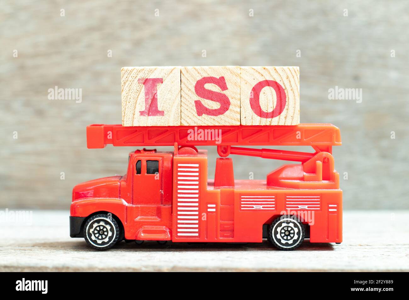 Feuerwehrwagen halten Buchstabenblock in Wort ISO ein Holzhintergrund Stockfoto