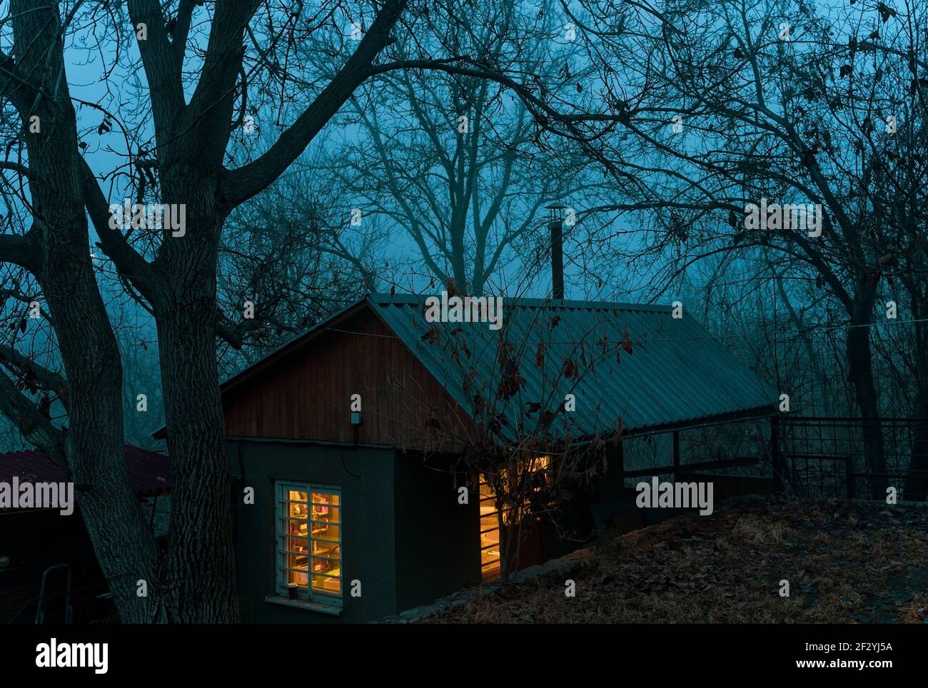 Kleines Haus mit Licht in den Fenstern im Nebel Stockfoto