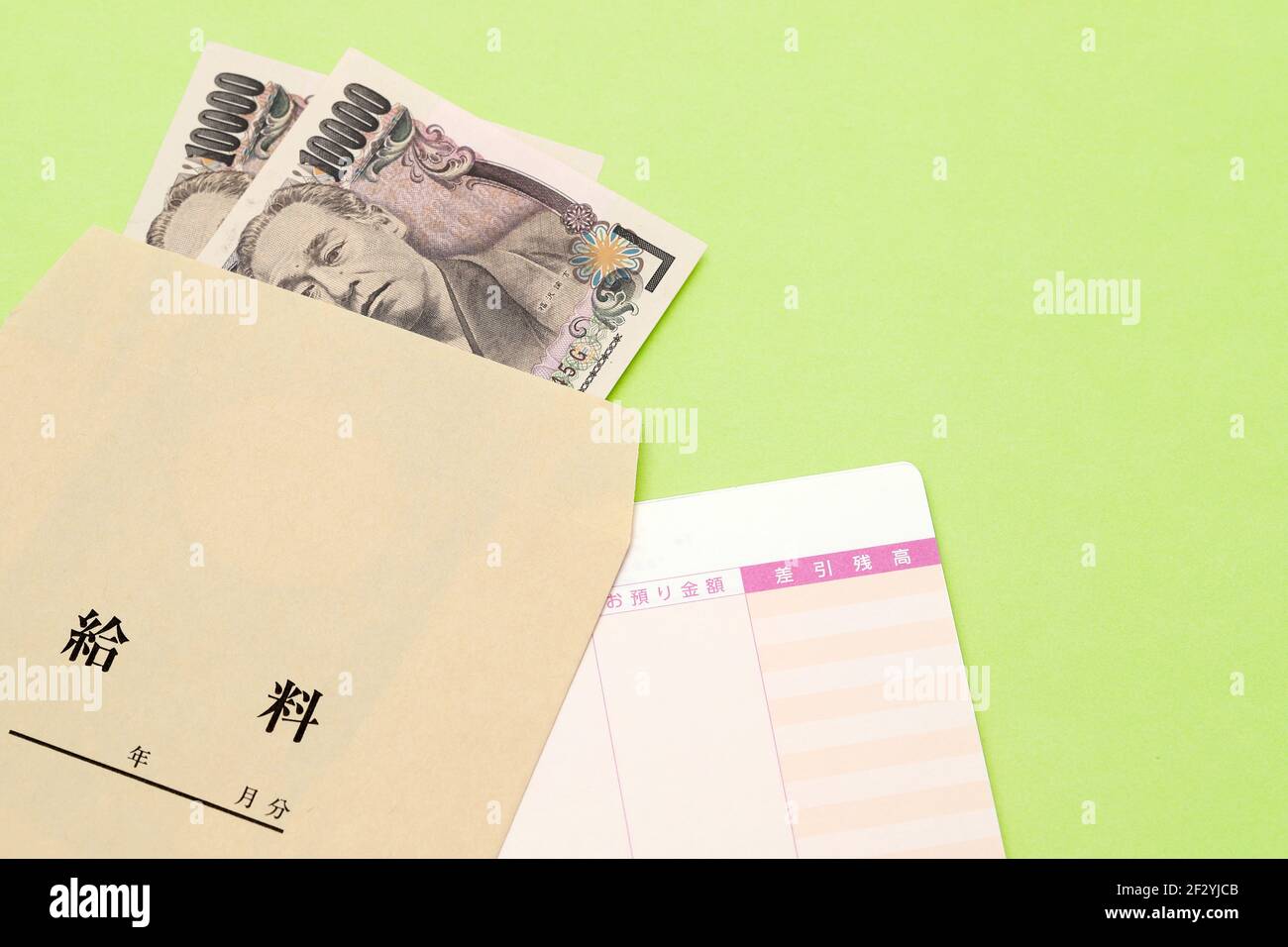 Japanisches Geld und Sparbuch mit Lohntüte isoliert auf weißem Hintergrund. Übersetzung: Jahr, Monat, Tag, Zahlung, Anzahlung, Saldo, Gehalt. Stockfoto