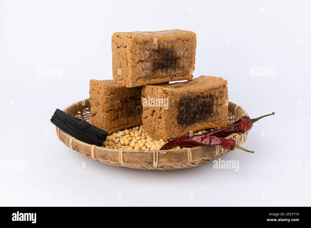 Meju, Bohnen, getrocknete Chili, Holzkohle und weißer Hintergrund. Koreanische traditionelle fermentierte Sojabohnen Essen. Stockfoto