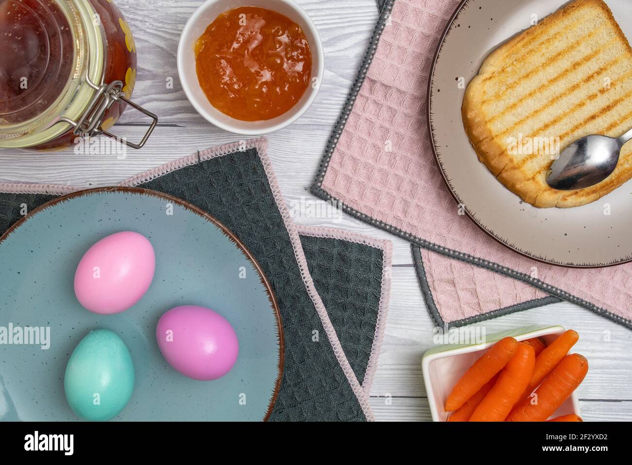 Farbiges Osterei auf dem Frühstückstisch mit Marmelade und geröstetem Brot. Stockfoto