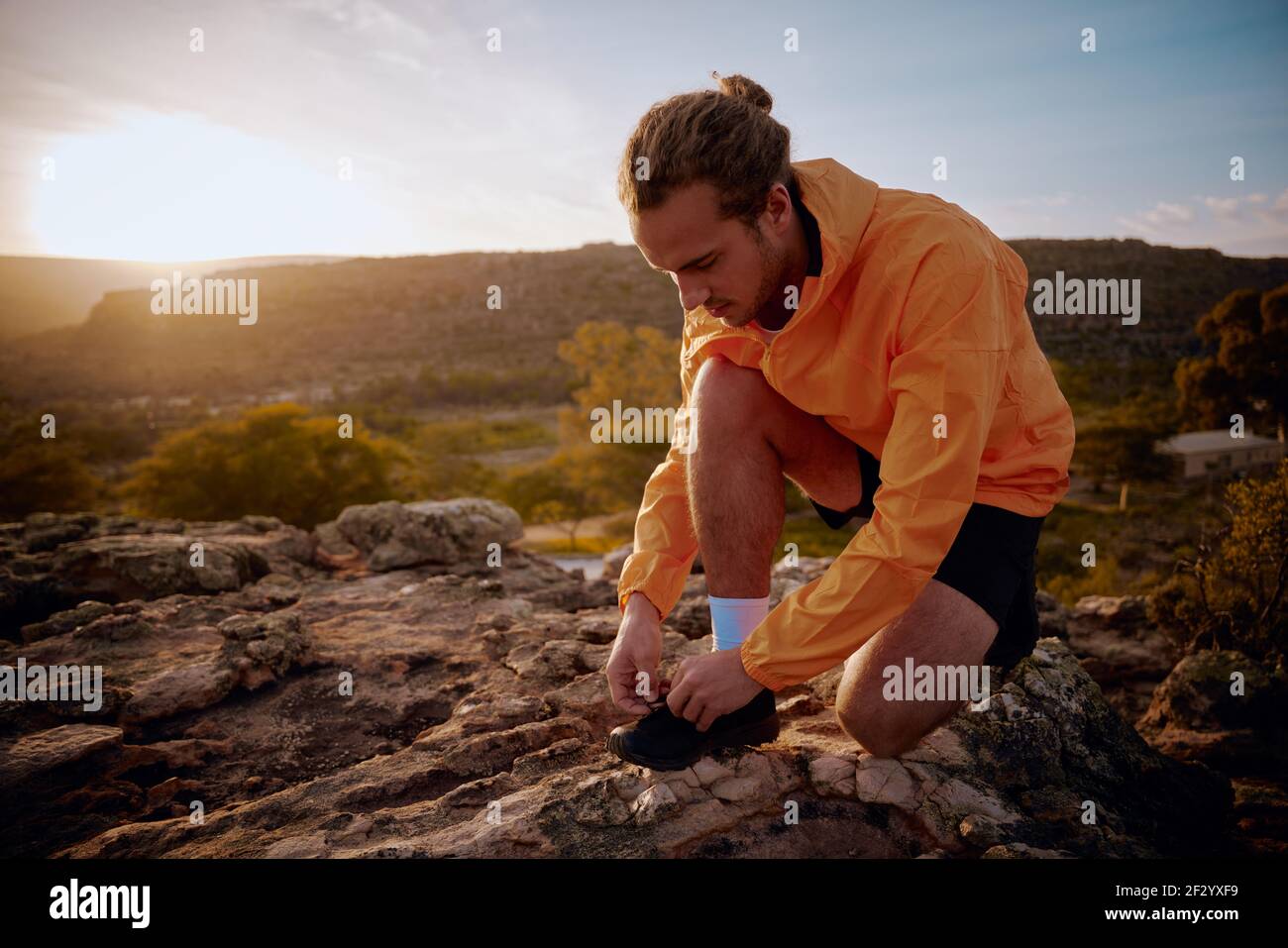 Junger Jogger bereitet sich auf den morgendlichen Lauf auf dem Bergweg gegen Sonnenaufgang am Morgen Stockfoto