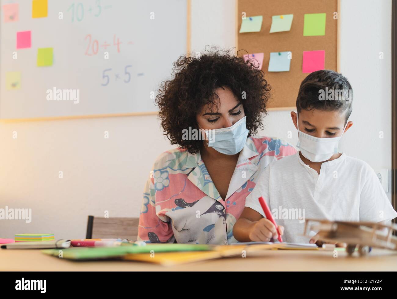 Lehrerin Frau mit Kind trägt Gesichtsschutzmaske in der Vorschule Präsenzunterricht während der Corona-Virus-Pandemie - Gesundheits- und Bildungskonzept Stockfoto
