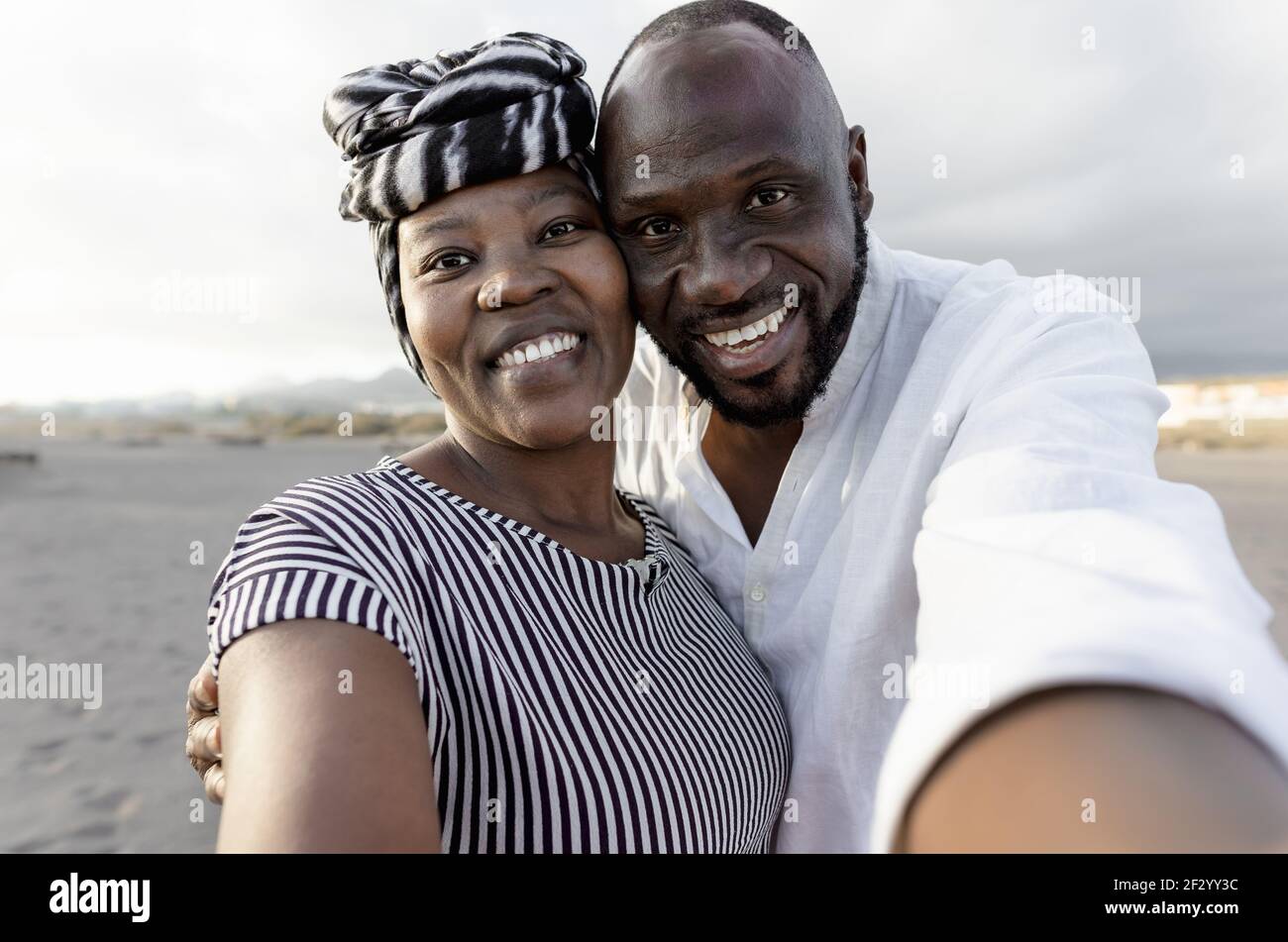 Glückliches afrikanisches Paar, das Selfie am Strand mit Handy macht Smartphone-Kamera während der Sommerferien - Liebe Beziehung Konzept Stockfoto