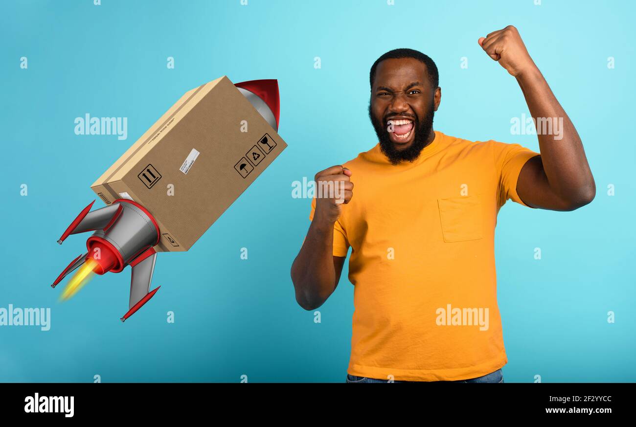 Schwarzer Mann ist glücklich, ein Paket zu erhalten. Konzept der schnellen Lieferung wie eine Rakete. Cyan Hintergrund Stockfoto